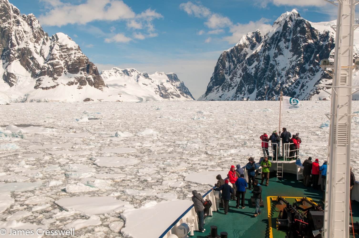 A photograph of a ship pushing through ice in Antarctica on a PolarWorld Travel placed cruise