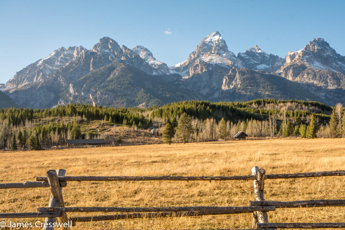 A photograph with a fence in the foreground and mountains behind, the Grand Teton Mountains, taken on a GeoWorld Travel USA geology trip, tour and holiday