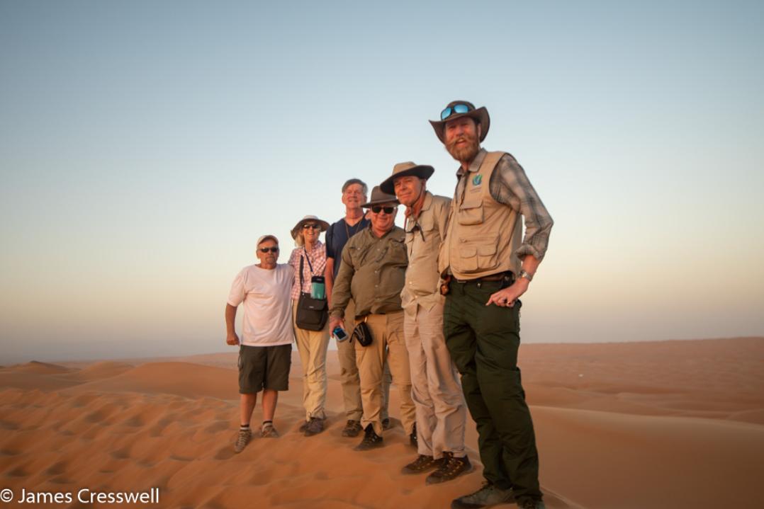 A photograph of six people standing on top of a desert dune in the Wahiba Sands, taken on a GeoWorld Travel Oman geology trip, tour and holiday