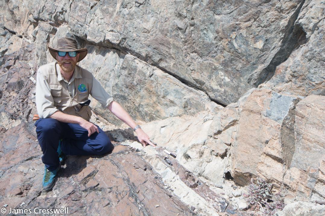 A photograph of James Cresswell pointing to the Moho in Wadi al Abyad, taken on a GeoWorld Travel Oman geology trip, tour and holiday