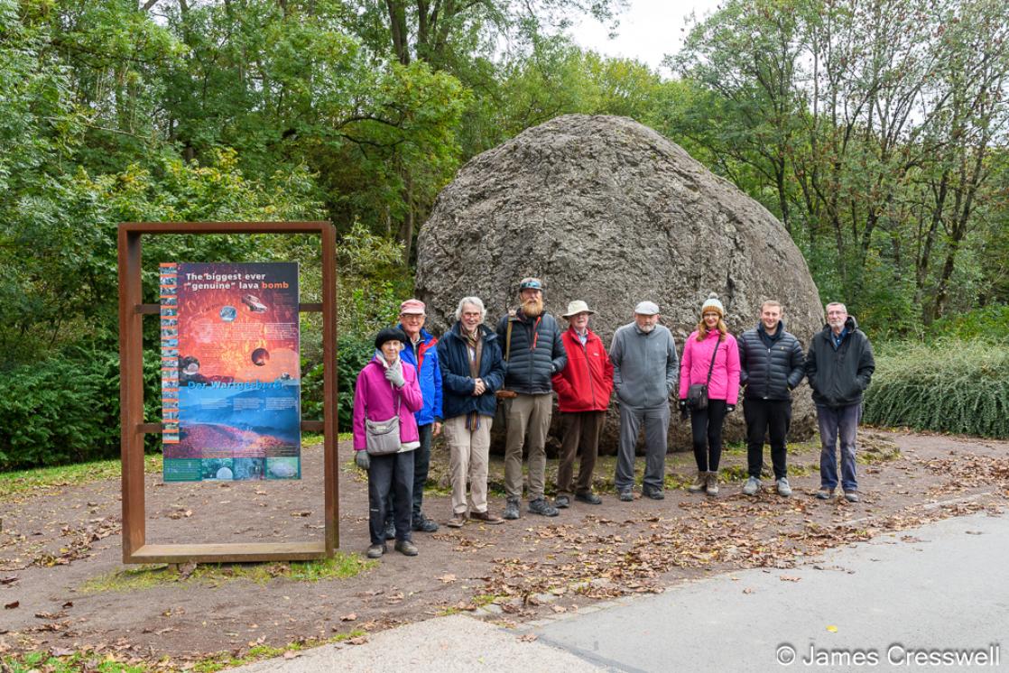 A group of people standing in front of a huge rock ball